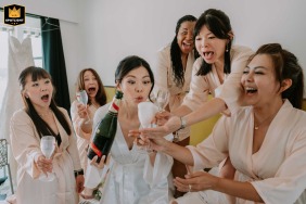 In Villefranche-sur-Mer, France, the bride and her bridesmaid react with surprise as the champagne overflows during a toast in the getting ready room.